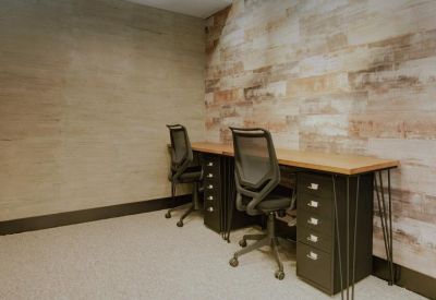 Dual workstation setup with black ergonomic chairs and rustic wood-paneled feature wall.