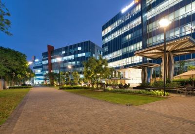 Modern outdoor walkway and seating area at night with illuminated office buildings.