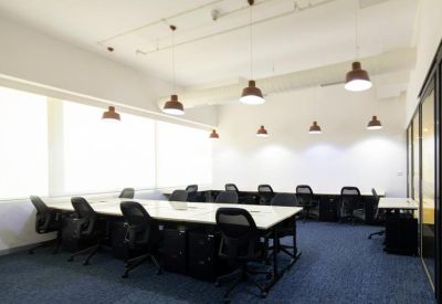 Spacious shared workspace with long white tables and ergonomic black chairs.