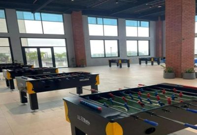 Bright break room featuring several foosball tables and large windows with natural light.