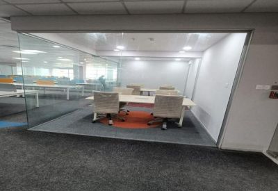 Small glass-partitioned meeting room with a white table and modern office chairs.