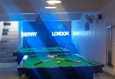 Lounge area featuring two green pool tables under blue accent lighting.