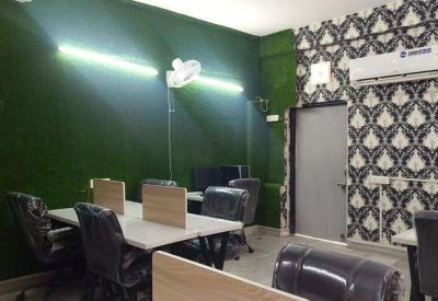 Coworking space with a green grass-textured wall and white desks.