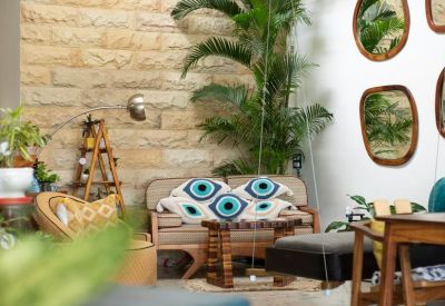 Bohemian lounge area with brick wall, large palm plant, and evil-eye patterned cushions.