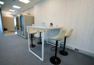 High-top collaboration table with sleek white stools in an open-plan area.