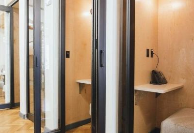 Row of private acoustic phone booths with glass doors and wooden interiors.