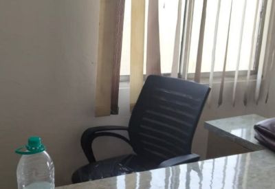 Close-up of a desk with a water bottle and an office chair by a window.
