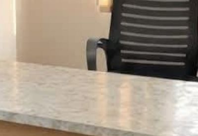 A marble-textured desk surface positioned in front of a modern black office chair.
