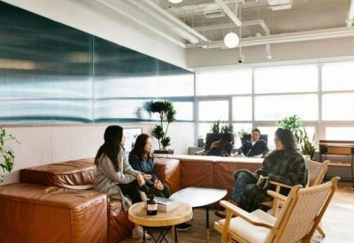 Lounge area featuring a tan leather sectional sofa, wooden armchairs, and a decorative mural wall.