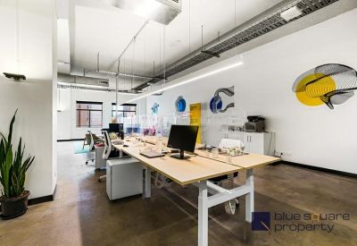 Spacious open-plan office with timber desks and colorful wall art.