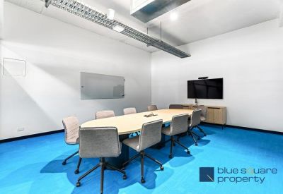 Modern conference room with a blue floor and large screen.