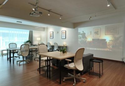 Bright coworking space featuring wooden tables, ergonomic chairs, and a media projector.