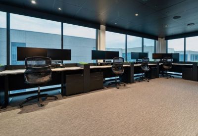 Row of modern height-adjustable desks positioned along a large window wall.