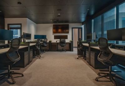 Open-plan workspace with multiple ergonomic workstations, dual monitors, and dark grey finishes.
