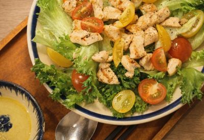 Close-up of a fresh chicken salad with cherry tomatoes in a ceramic bowl.