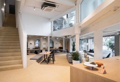 Spacious, double-height communal lounge with a staircase and warm lighting at 18 Ratchadaphisek Road.