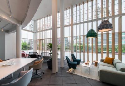 Bright coworking space with floor-to-ceiling windows, timber louvers, and colorful pendant lights.