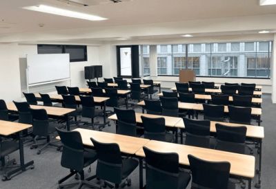 Bright classroom-style training room with rows of desks and black office chairs.