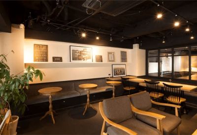 Cozy lounge area featuring round cafe tables, plush armchairs, and a wall of framed art.