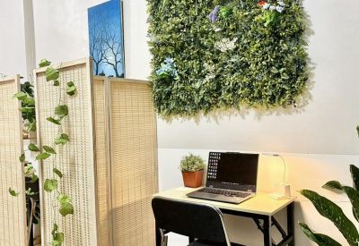 Cozy desk nook with a laptop and lamp situated next to a decorative green plant wall.