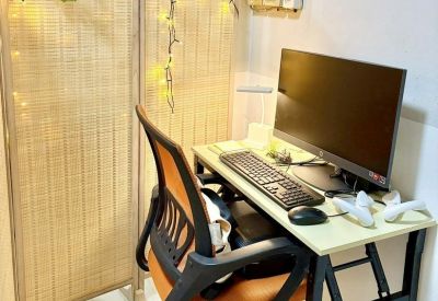 Private workstation with an orange ergonomic chair and desktop monitor behind a wicker screen.