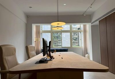 Bright open-plan workspace featuring a large wooden desk and soft pendant lighting.