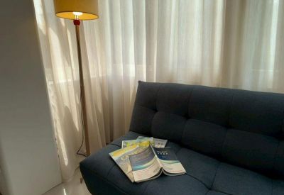 Cozy lounge area with a dark blue sofa and a warm floor lamp beside white curtains.