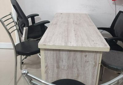 Compact desk setup with a light wood grain finish and comfortable ergonomic chairs.