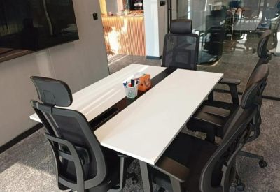 Professional workspace with four black ergonomic chairs and a shared white desk.