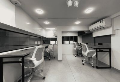 Bright coworking area featuring multiple workstations with white ergonomic chairs.