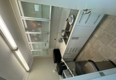 Kitchenette with white cabinetry, stainless steel sink, and appliances.