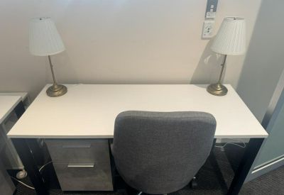 White private workstation with two lamps and a grey chair.