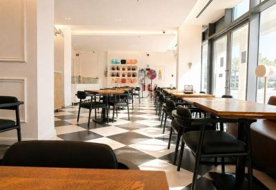 Brightly lit seating area with floor-to-ceiling windows and a colorful art wall in the background.