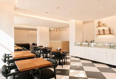 Dining area featuring wooden tables, black chairs, and a white service counter with glass displays.