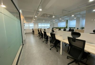 View of several white workstations with ergonomic chairs in a bright, modern room.