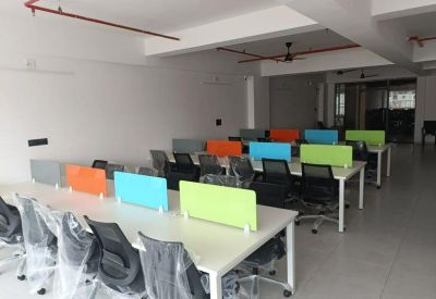 Spacious open-plan workspace featuring multiple rows of desks with colorful acoustic panels