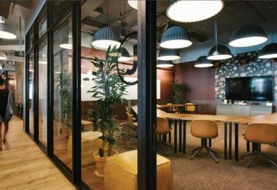 Glass-walled conference room with a long table, tan chairs, and multiple pendant lights.
