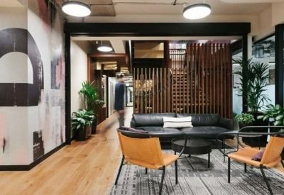 Lounge area featuring a black leather sofa, tan leather armchairs, and patterned mural wall.