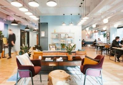 Bright breakout lounge with colorful armchairs, wooden coffee table, and large windows.