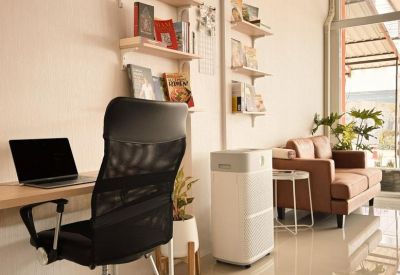 Bright coworking area with a laptop desk, air purifier, and leather sofa.