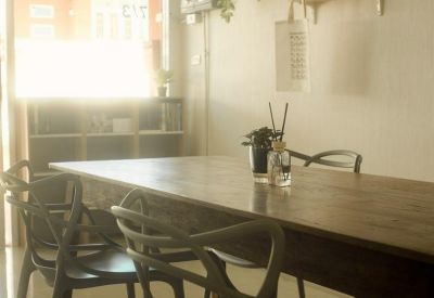 Long wooden communal table with designer chairs and wall-mounted bookshelves.
