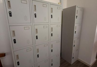 Row of gray multi-tier metal lockers in a brightly lit corridor.