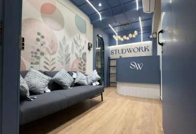 Reception area of Skyblu 72 Corp with a botanical mural, grey sofa, and branded blue desk.