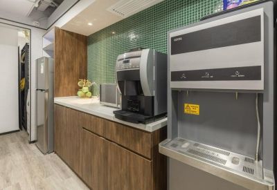 Communal kitchen area with coffee machine, water dispenser, and green tile backsplash.