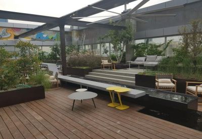 Outdoor lounge area with wooden flooring, modern yellow tables, and a ceiling fan.