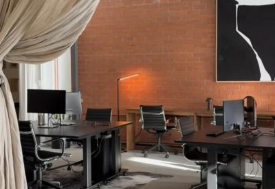 Modern industrial workspace with exposed brick walls, workstations, and soft linen drapes.
