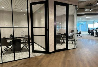 Private glass-walled office suites with black frames and light wood flooring.