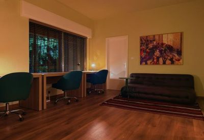 Cozy lounge area featuring a dark leather sofa, colorful rug, and private work desks.