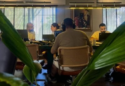 Team working at desks in a modern office with large windows and indoor plants.
