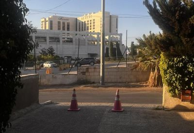 View from the office entrance showing orange traffic cones and a distant building under a clear blue sky.